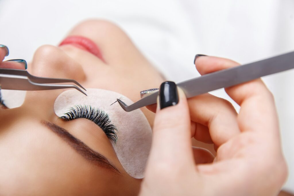 Eyelash Extension Procedure. Woman Eye with Long Eyelashes. Close up, selective focus